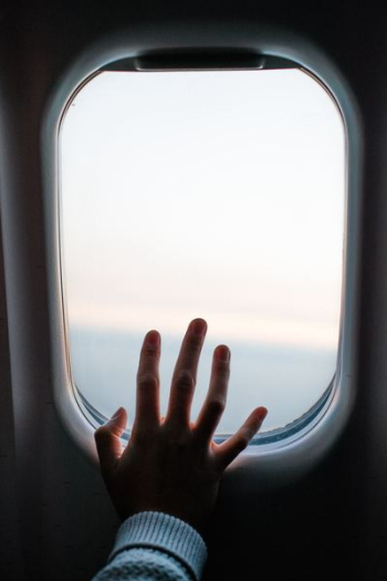 person touching airplane window person touching airplane window