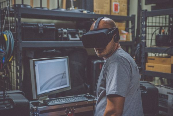 person using black VR Headset in front of computer person using black VR Headset in front of computer