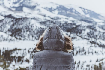 person wearing black parka hoodie in front of mountain person wearing black parka hoodie in front of mountain