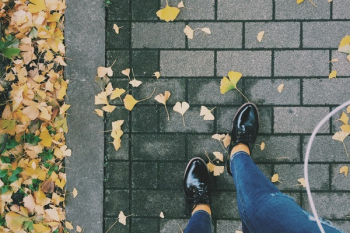 Person Wearing Black Patent Leather Dress Shoes on Gray Brick Pathway