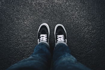 person wearing black sneakers standing on black surface person wearing black sneakers standing on black surface