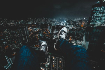 person wearing blue jeans facing cityscape during nighttime