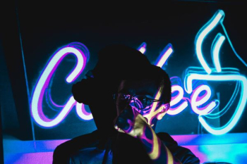 person wearing eyeglasses with shadow near neon light signage