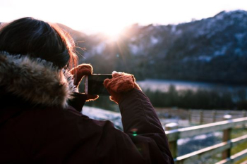 person wearing parka holding phone taking photo person wearing parka holding phone taking photo