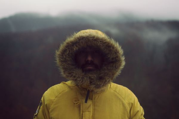 person wearing yellow parka jacket near mountain person wearing yellow parka jacket near mountain