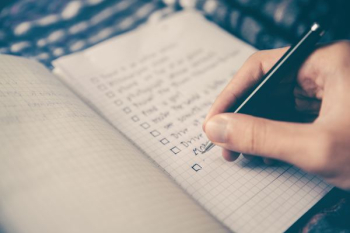 person writing bucket list on book person writing bucket list on book