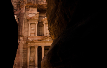 Petra treasure ancient architecture building inside canyon dark rock walls frame famous world heritage touristic site