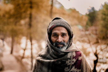 Photo of an elderly man smiling wearing a knit cap and scarf Photo of an elderly man smiling wearing a knit cap and scarf