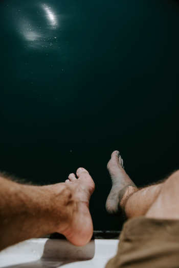 Photo of Bare Feet Dangling Above Body of Water Photo of Bare Feet Dangling Above Body of Water