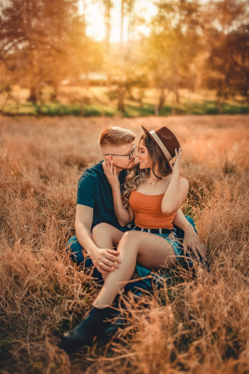 Photo of Kissing Couple Sitting on Grass