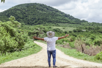 Photo of Man Wearing Hat While Standing on Dirt Road Photo of Man Wearing Hat While Standing on Dirt Road