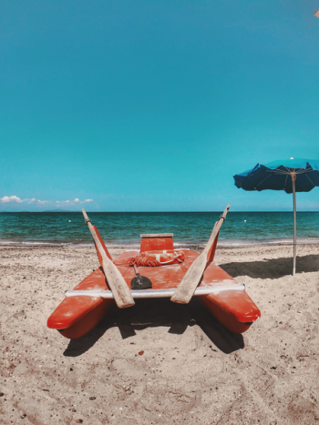 Photo of Red Watercraft on Seashore Photo of Red Watercraft on Seashore