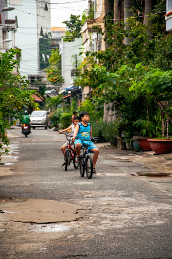 Photo of Two Boys Riding Bikes on the Street Photo of Two Boys Riding Bikes on the Street