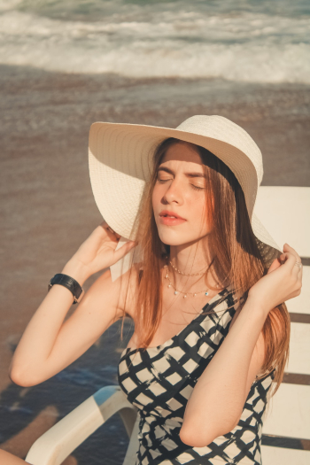 Photo of Woman Sitting on Sun Lounger While Holding Her Sun Hat Photo of Woman Sitting on Sun Lounger While Holding Her Sun Hat
