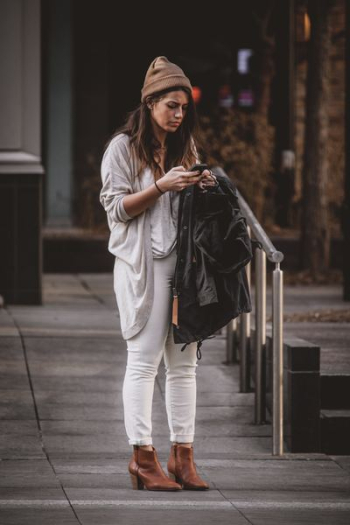 photography of woman in gray cardigan using her mobile phone