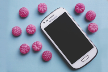 Pink candies and white smartphone Pink candies and white smartphone