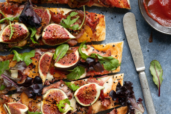 Pizza with tomatoes ham mozzarella and figs flat lay sliced up Pizza with tomatoes ham mozzarella and figs flat lay sliced up
