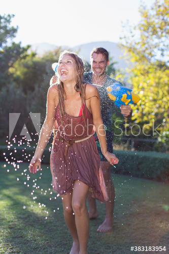 Playful couple with squirt gun in backyard Playful couple with squirt gun in backyard