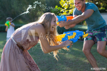 Playful family with squirt guns in backyard Playful family with squirt guns in backyard