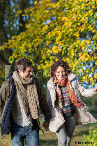 Playful young couple running in autumn park