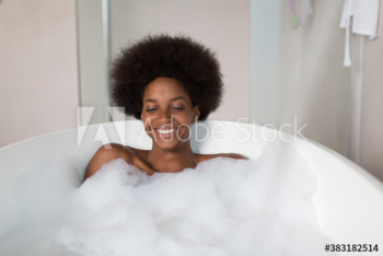 Portrait carefree young woman with afro enjoying bubble bath
