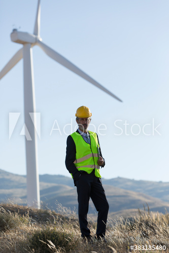 Portrait confident male engineer below wind turbine Portrait confident male engineer below wind turbine