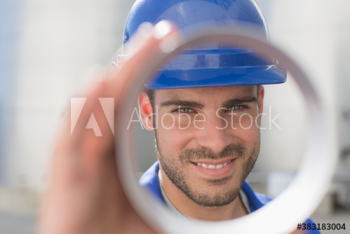 Portrait confident male worker looking through tube Portrait confident male worker looking through tube