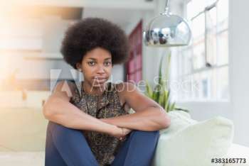 Portrait confident young woman with afro on sofa Portrait confident young woman with afro on sofa