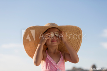 Portrait cute girl in sun hat covering eyes with seashells Portrait cute girl in sun hat covering eyes with seashells