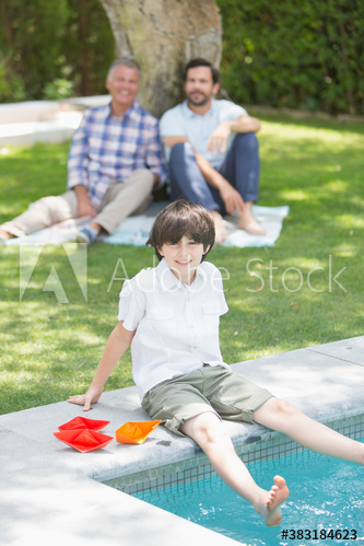 Portrait happy boy dipping feet in swimming pool Portrait happy boy dipping feet in swimming pool
