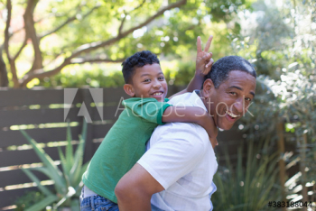 Portrait happy grandfather piggybacking grandson in backyard Portrait happy grandfather piggybacking grandson in backyard