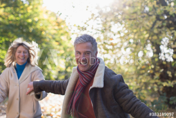 Portrait happy mature couple running in woods