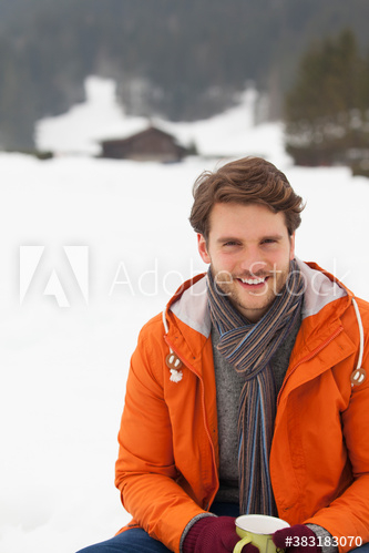 Portrait happy young man drinking hot cocoa in snow Portrait happy young man drinking hot cocoa in snow