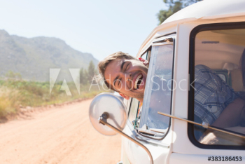 Portrait happy young man leaning out sunny van window Portrait happy young man leaning out sunny van window