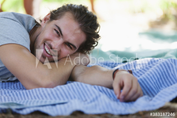 Portrait happy young man relaxing on picnic blanket Portrait happy young man relaxing on picnic blanket