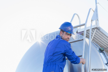 Portrait male worker climbing milk tanker ladder Portrait male worker climbing milk tanker ladder