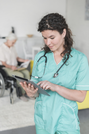 Portrait of female nurse with stethoscope around her neck using digital tablet