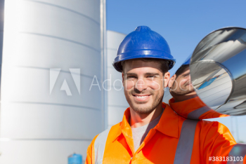 Portrait smiling male worker carrying steel tank Portrait smiling male worker carrying steel tank