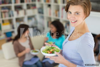 Portrait smiling woman eating salad with friends in living room Portrait smiling woman eating salad with friends in living room