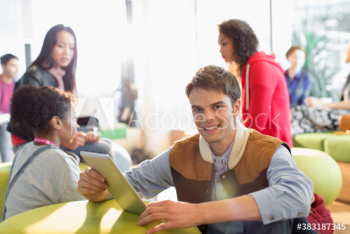 Portrait young male college student using digital tablet in student lounge Portrait young male college student using digital tablet in student lounge