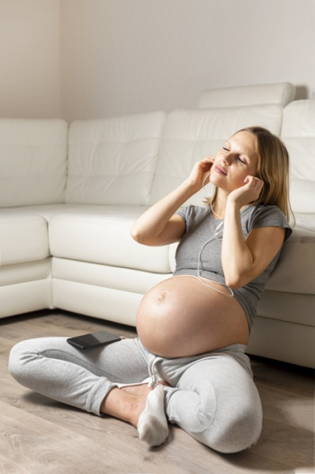 Pregnant blonde woman listening music Free Photo