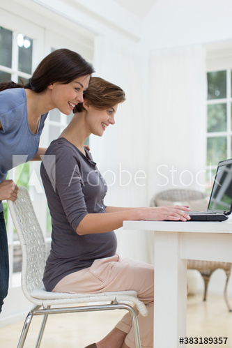 Pregnant woman and friend using laptop Pregnant woman and friend using laptop