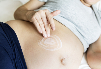 Pregnant Woman Applying Cream on Stomach While Lying on Bed