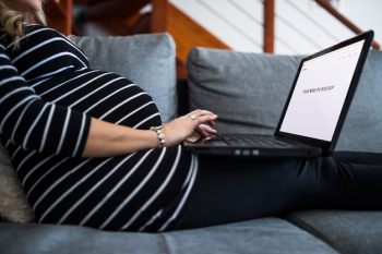 Pregnant woman on couch using computer