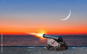 Ramadan Concept - Ramadan kareem cannon with crescent and fireworks - Night sky with moon in the clouds at sunset