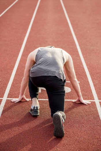 Rear view of a male athlete taking position on red race track for running Free Photo