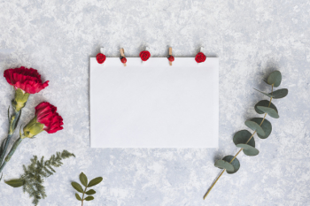 Red carnation flowers with paper on table Red carnation flowers with paper on table