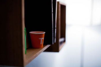 red disposable cup on brown wooden shelf red disposable cup on brown wooden shelf