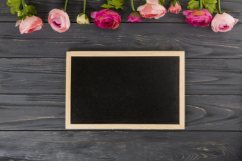 Rose flowers with big chalkboard on wooden table Rose flowers with big chalkboard on wooden table