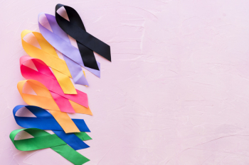 Row of bright colorful awareness ribbon on pink rough background
